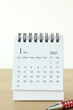 © Marinela - January first 2027 calendar month with pen on a wooden desk and white background. Copy space. New year plan, goal, and resolution concept.