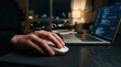 © Panuwat - A person performing digital tasks using a white computer mouse and laptop at night.