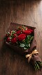 © Luan - Beautiful bouquet of red roses wrapped in brown paper with a gold ribbon on wooden surface
