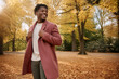 © Milan - Happy Black man walking in autumn park. Smiling African American male wearing stylish coat enjoying fall nature
