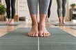 © PixelFusion Creation - Close-up of women standing barefoot on yoga mats during a group class, emphasizing balance, alignment, mindfulness, and wellness.