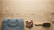 © Riverruno - Folded grey knitted sweater with wooden buttons and a brush on a wooden table