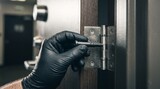 Gloved hand removing metal pin from heavy door hinge in hallway