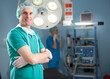 © Fatih - Portrait of confident male surgeon standing with arms crossed in hospital operating room.