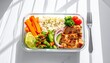 © imi - Glass container filled with grilled chicken rice and fresh vegetables for healthy lunch meal preparation.