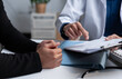 © Father_Studio - Doctor reviewing medical records with a patient during consultation, explaining healthcare documents, diagnosis, treatment options, clinical results, insurance and personalized care planning.