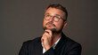 © Nick Freund - Nachdenklicher Mann mit Brille und Bart stützt Kinn ab, dunkler Hintergrund, geeignet für Business- und Beratungswerbung.