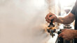 © Dezayn - Barista tamping fresh coffee grounds into an espresso machine portafilter, creating a cloud of aromatic coffee dust
