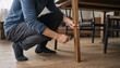 © MdNiloy - Homeowner working on furniture assembly by tightening screws on a wooden dining table leg with home improvement wooden floor dining room screwdriver handyman carpentry woodwork housework