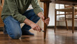 © MdNiloy - Man assembling or repairing wooden table legs kneeling on hardwood floor at home with table leg furniture repair home assembly carpenter working diy project handyman tools fixing furnitur