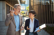 © Davor - Two business professionals discussing reports outside modern office