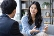 © kayden - Asian businesswoman communicating with male colleague, discussing project, collaborating in modern office lounge