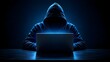 © Hamzah - Anonymous hacker in hooded sweatshirt using laptop in dark room symbolizing cybercrime and network security threat
