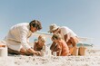 © Breezze - Family building a sandcastle on a sunny beach, featuring damp sand and bright summer light for family vacation and travel campaigns with copy space