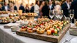 © MOSTHASNAHENA - A rustic wooden serving board filled with gourmet appetizers and finger foods at a festive social gathering or wedding reception