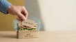 © KohXD - Person opening box with sandwich visualizing minimum viable product concept through assembling essential layers