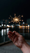 © britaseifert - Male hand holding a single lit yellow sparkler at night