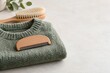 © Jibber  - Grüner Strickpullover mit Wollkamm und Kleiderbürste als Motiv für Kleidungspflege
