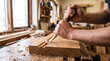 © tangmo.pa - Hands of a carpenter carving a wooden plank with a sharp chisel in workshop