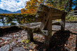 © MORIO - 秋の気配が漂う公園の木製ベンチと落ち葉、背景の紅葉と山々の風景