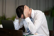 © Ekkasit A Siam - Stressed adult Caucasian businessman holding head beside laptop in modern coworking office, experiencing workplace pressure while managing difficult project tasks and serious business problem.