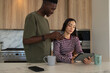 © WavebreakMediaMicro - Diverse couple sitting at marble island using tablet while man holding credit card and smartphone