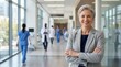 © Panuwat - Confident mature woman in a grey suit smiling in a hospital hallway.