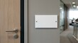 © Mookchan - Blank white rectangular sign mockup mounted on grey wall next to modern wooden office door in professional workplace