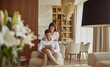 © Adeeba - Indoor, full shot of a young adult couple in a lounge with laptop