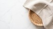 © usda - Minimalist top view of a woven wicker basket with linen napkin on white marble background with copy space