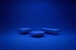 © Aza - Three geometric platforms in different shapes and heights arranged in a minimalist blue studio setting.