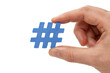 © PixelWright - A hand holding a small blue plastic hashtag symbol against a plain white background, for social media, concepts isolated on, a transparent background
