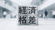 © Blue Studio - 「経済格差」の文字を刻んだブロックの概念ビジュアル