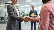 © EventLogic Studio - Business partners handshake in office with man on crutches in background.