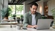 © junaied - Smiling man working on laptop at cafe table with coffee and smartphone