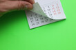 © splitov27 - Hand flips through paper calendar on a green background