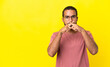 © luismolinero - Young latin man isolated on yellow background showing a sign of silence gesture