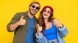 © Yellow Blossom - Funky young couple in casual summer clothes giving thumbs up against a bright yellow background.