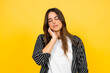 © Daniel - Young woman feeling discomfort and pain in her neck area, gently massaging her sore muscles with closed eyes against a bright yellow background, representing fatigue and pressure