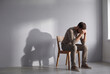 © Rani - Depressed man sitting alone on a minimalist wooden chair, head lowered in hands