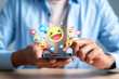 © Kiattisak - Social media network communication and online engagement reaction. Man hand holding smartphone using emoji emoticon heart like and laugh face.