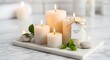 © Imam Muhamad Yusup - Peaceful Earth Day Candle Display with Natural Stones and Fresh Green Leaves on a Marble Surface for Eco Friendly Home Decor and Relaxation