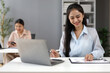 © Kainnika - Asian businesswoman reviewing documents and working with tablet in office.
