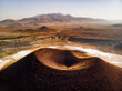 © Amazing Aerial - Aerial view of the volcanic crater and caldera cone of Lake Meke surrounded by arid landscape and salt flats with distant mountains on the horizon in Karapinar, Konya, Turkiye.