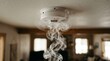 © olga_demina - A close up view of a white smoke detector mounted on a ceiling as delicate wisps of grey smoke swirl upward toward the safety device in a blurred indoor residential living space