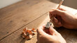 © Achmad - Hands sharpening a wooden pencil with a metal sharpener on a rustic table