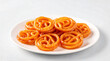 © Grow with Dani - A plate full of glistening sweet jalebis, a popular Indian dessert, arranged invitingly on a white plate