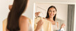 © Prostock-studio - Smiling Young Woman With Light Skin Tone Holding Two Colorful Clothes In Front Of Mirror At Home Setting, Enjoying Dressing Up And Exploring Fashion Choices In A Stylish Room. Fashion Concept.