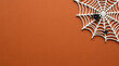 © Sumi - White spider web with black spiders on orange background for Halloween party decoration