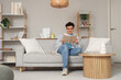 © Pixel-Shot - Handsome young man reading book on sofa at home